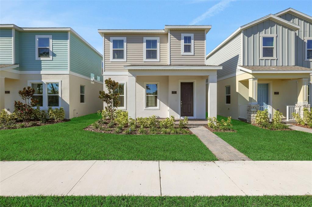 A two-story house with beige siding and a front porch sits between two neighboring homes — 13011 TRANQUIL WATER ALLEY, WINTER GARDEN, FL