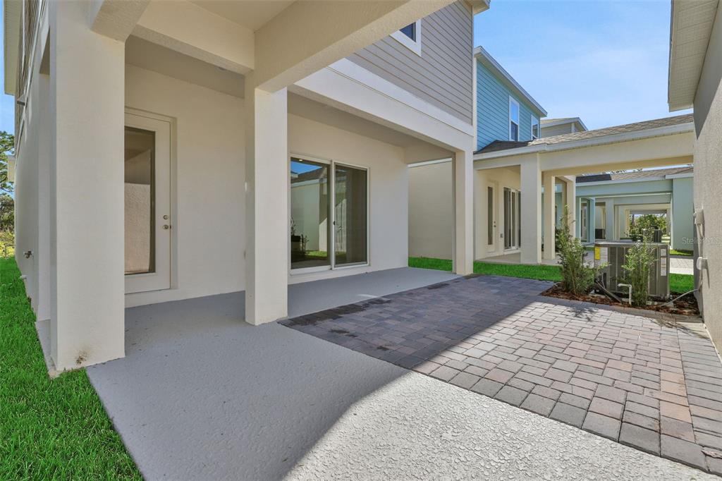 A covered concrete patio transitions into a paved area between two residential buildings — 13011 TRANQUIL WATER ALLEY, WINTER GARDEN, FL