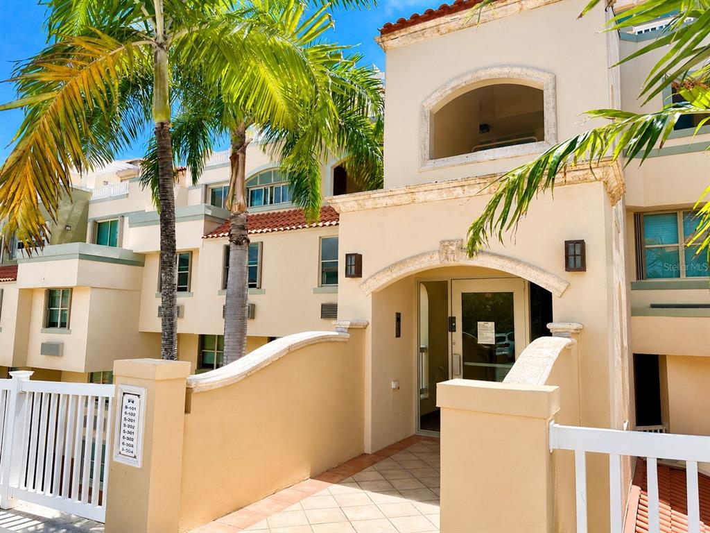 The exterior of a multi-story stucco building features a palm tree and a gated entrance — 285 PALMAS INN RD, PALMAS DEL MAR, UNIT 5102, HUMACAO, PR