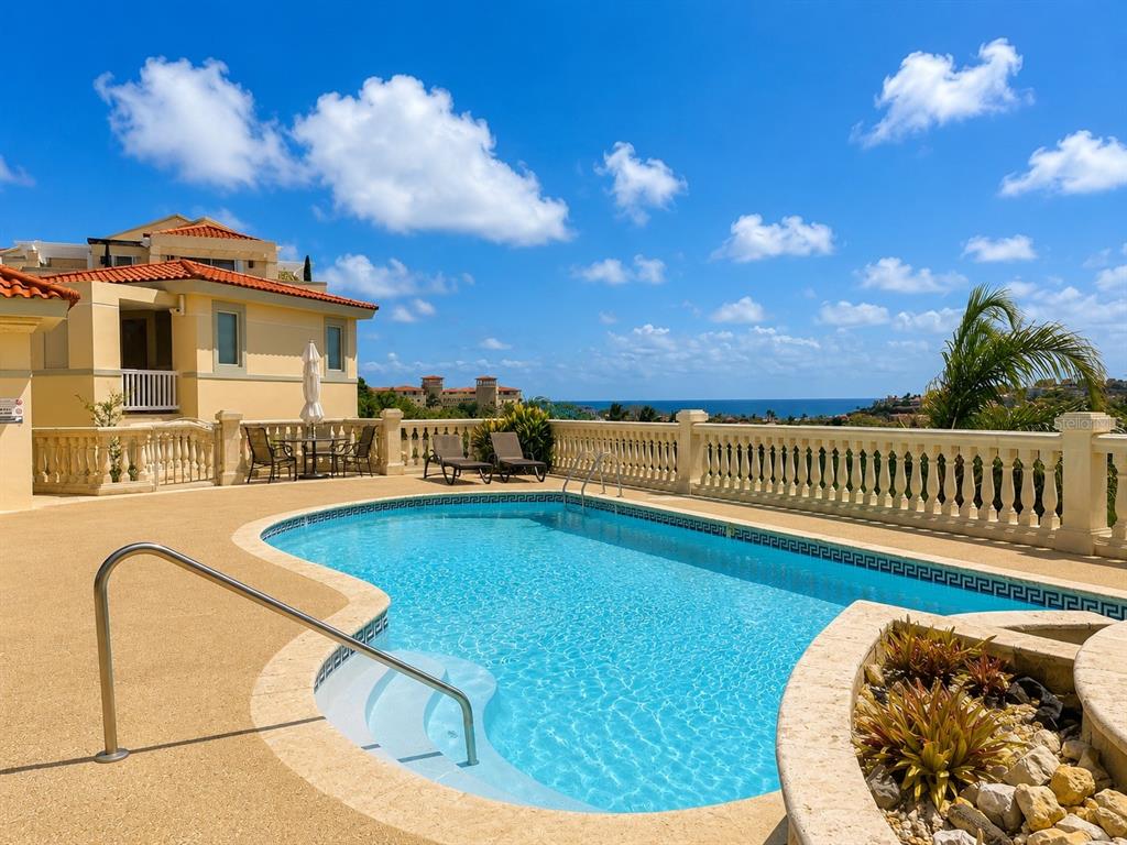 A swimming pool with a metal handrail sits on a patio overlooking the ocean — 285 PALMAS INN RD, PALMAS DEL MAR, UNIT 5102, HUMACAO, PR