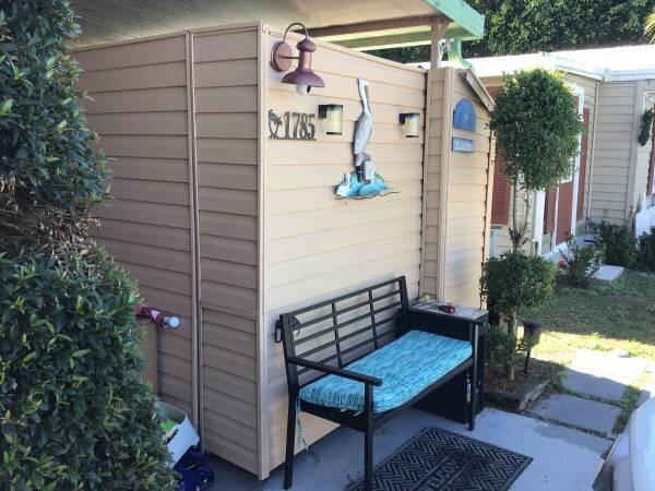 A tan vinyl-sided exterior wall features a house number, a pelican decoration, and a bench — 1785 SW Diana Terrace, Stuart FL 34997, STUART, FL