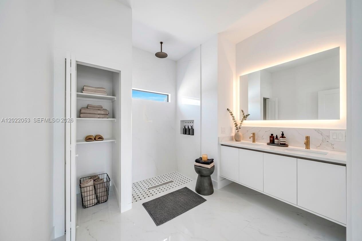 A modern bathroom features a walk-in shower, double vanity, and built-in shelving with white finishes — 3286 EAGLE PASS ST, North Port FL 34286, NORTH PORT, FL