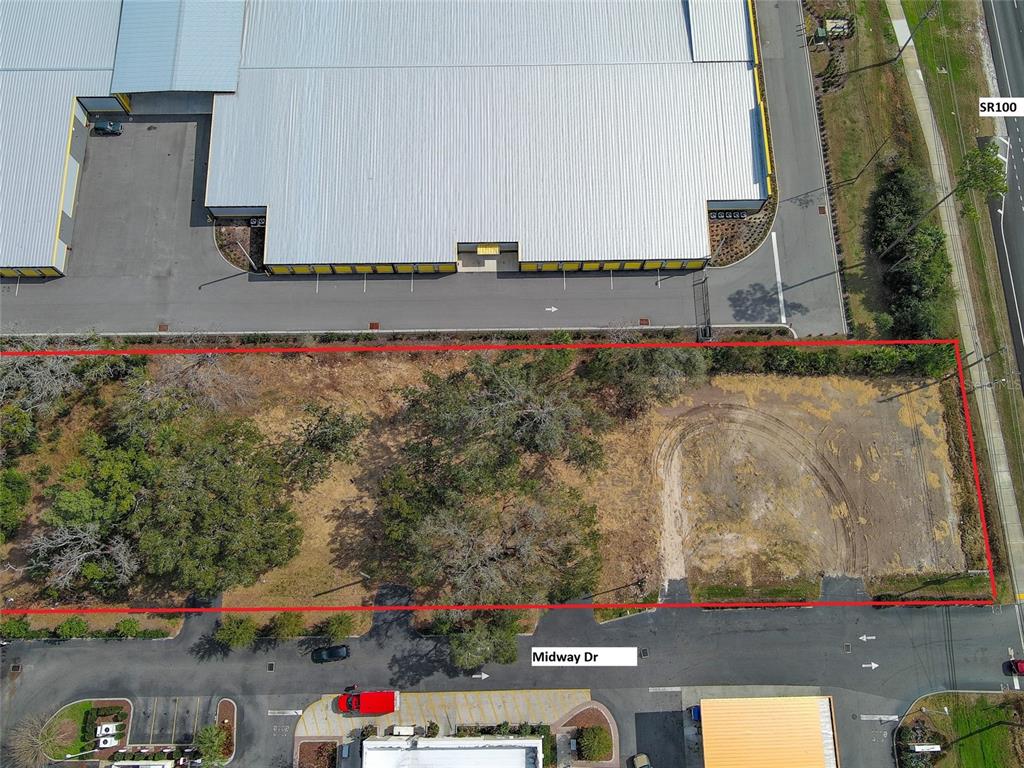 An aerial view shows a vacant, partially cleared rectangular lot bordered by a road and buildings — 2 MIDWAY DRIVE, PALM COAST, FL