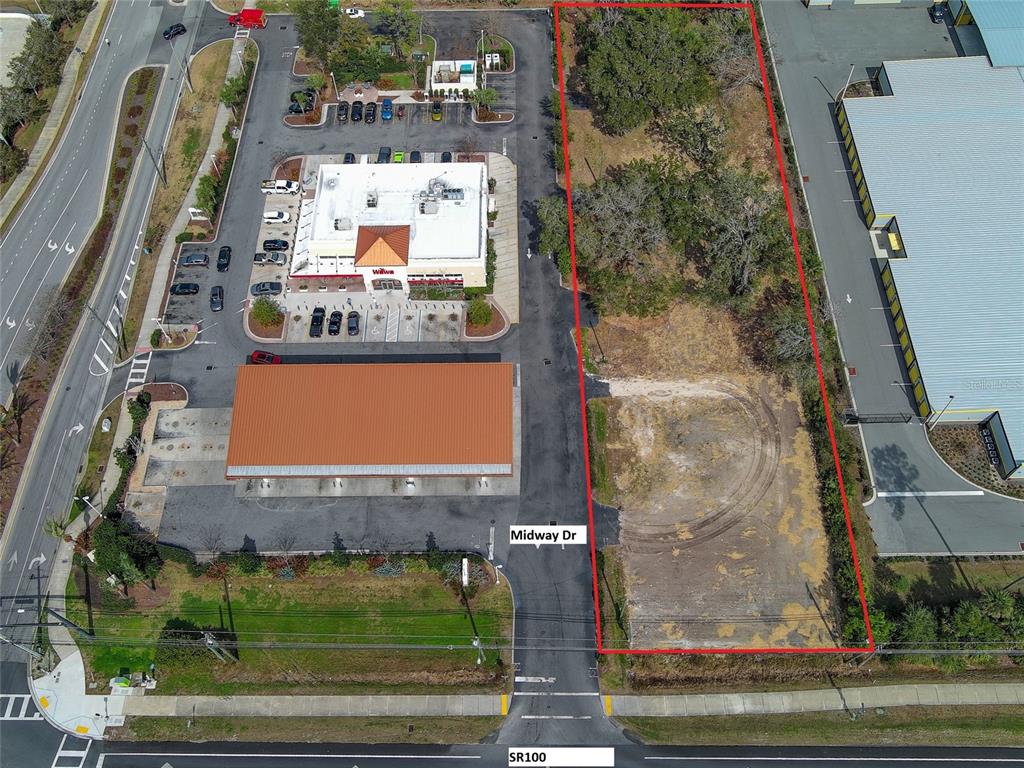 An aerial view shows a vacant rectangular lot outlined in red next to a commercial property — 2 MIDWAY DRIVE, PALM COAST, FL