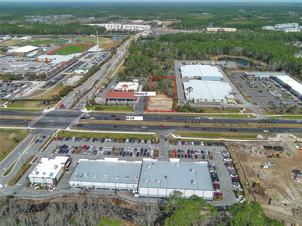 An aerial view shows a vacant rectangular lot outlined in red between two commercial buildings — 2 MIDWAY DRIVE, PALM COAST, FL