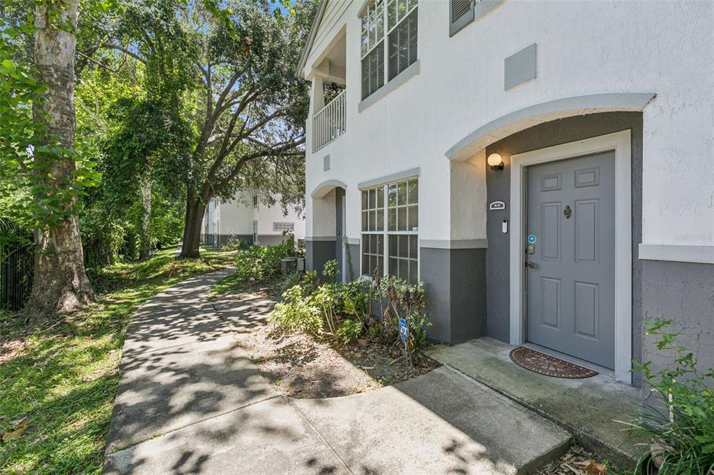 A concrete walkway leads to the gray front door of a two-story apartment building — 4316 S KIRKMAN ROAD UNIT 1614, ORLANDO, FL