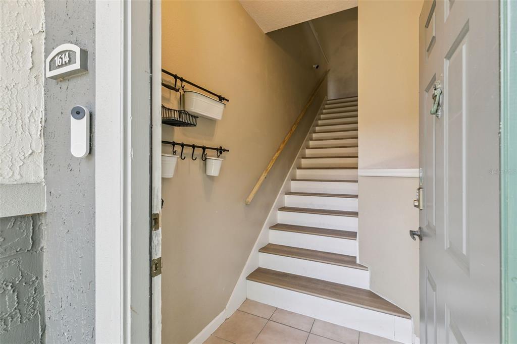 An open front door reveals a tiled entryway leading to a staircase with wood treads — 4316 S KIRKMAN ROAD UNIT 1614, ORLANDO, FL