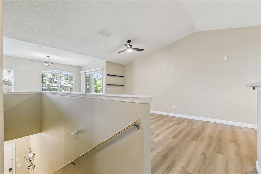 An open-concept living area features vaulted ceilings, wood-look flooring, and a staircase with carpet — 4316 S KIRKMAN ROAD UNIT 1614, ORLANDO, FL