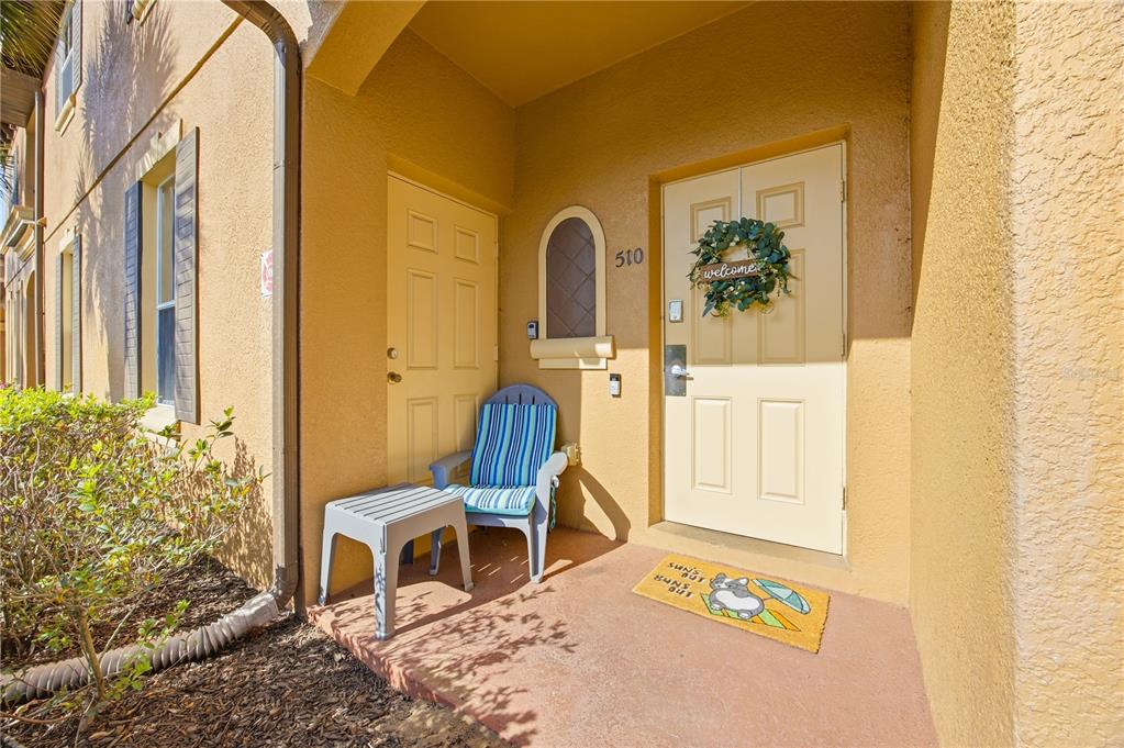 An exterior view of a building entrance with a door, a small table, and a chair — 510 CALABRIA AVENUE, DAVENPORT, FL