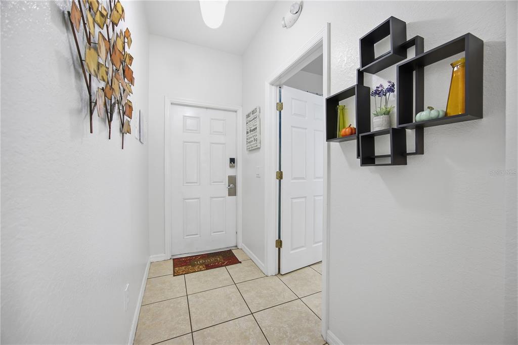 An entryway features tile flooring, a white front door, and a black wall-mounted shelf unit — 510 CALABRIA AVENUE, DAVENPORT, FL