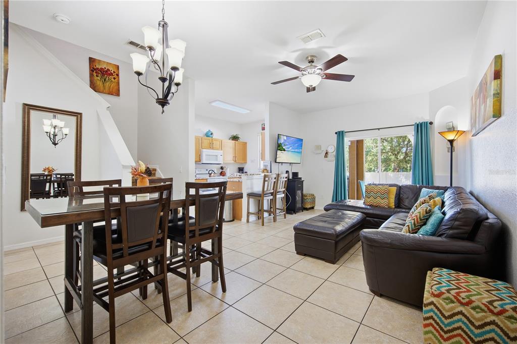 An open-concept living and dining area features tile flooring, a ceiling fan, and kitchen access — 510 CALABRIA AVENUE, DAVENPORT, FL