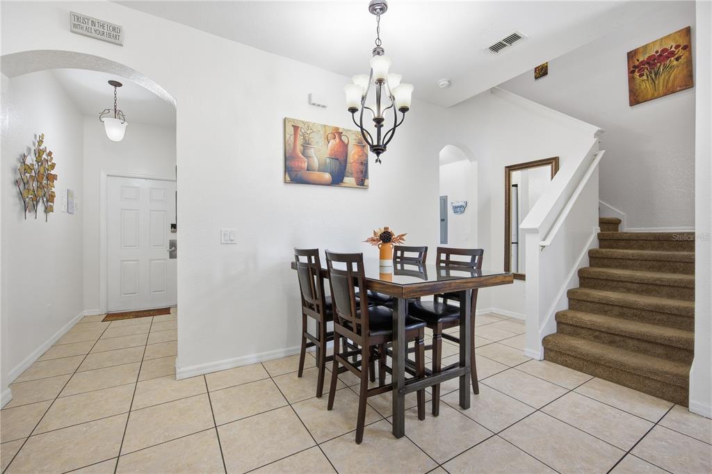 A dining area features a glass-topped table, dark wood chairs, tile flooring, and a staircase — 510 CALABRIA AVENUE, DAVENPORT, FL