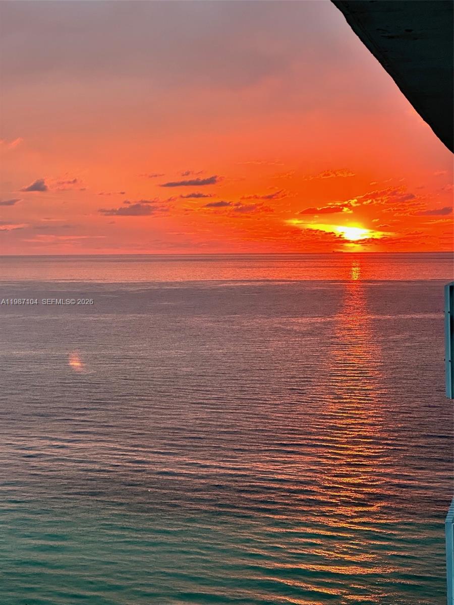 A vibrant sunset over the ocean viewed from a high-rise balcony — 6061 Collins Ave # 12D, Miami Beach FL 33140, MIAMI BEACH, FL