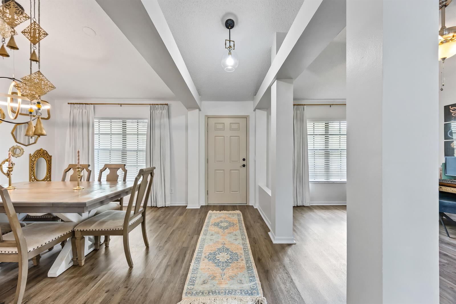 A dining area and entryway feature wood-look flooring, white walls, and a patterned runner rug — MELBOURNE, FL