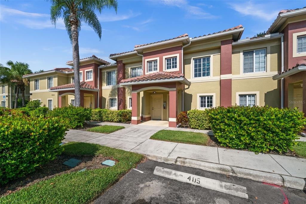 A two-story residential building with a tan stucco exterior, red accents, and a tiled roof — 9430 IVY BROOK RUN UNIT 405, FORT MYERS, FL