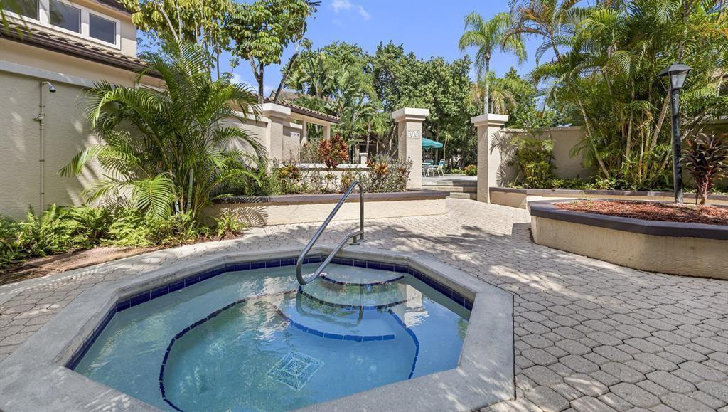 An outdoor hot tub with a metal handrail sits on a paved patio near landscaping — 4341 W Mcnab Road # 10, Pompano Beach FL 33069, POMPANO BEACH, FL