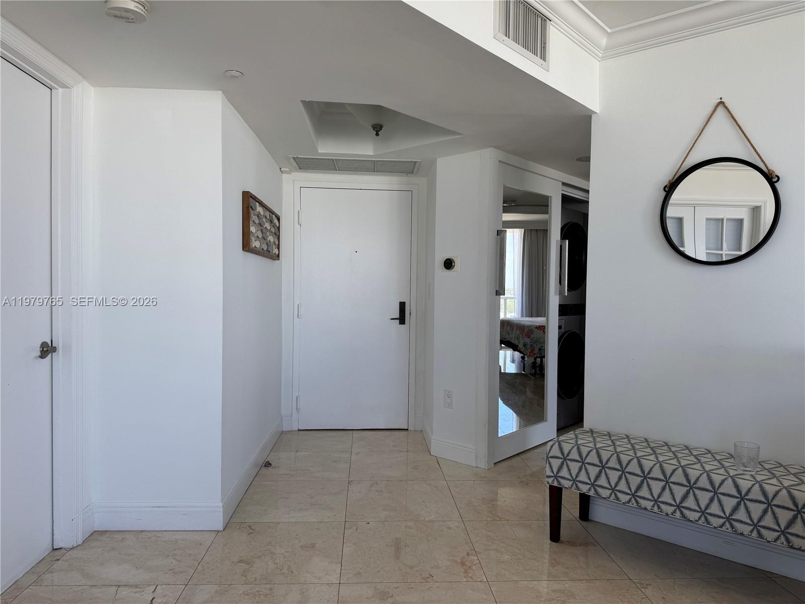 An entryway features tile floors, a white door, a mirror, and a patterned bench — 7330 Ocean Ter # D, Miami Beach FL 33141, MIAMI BEACH, FL