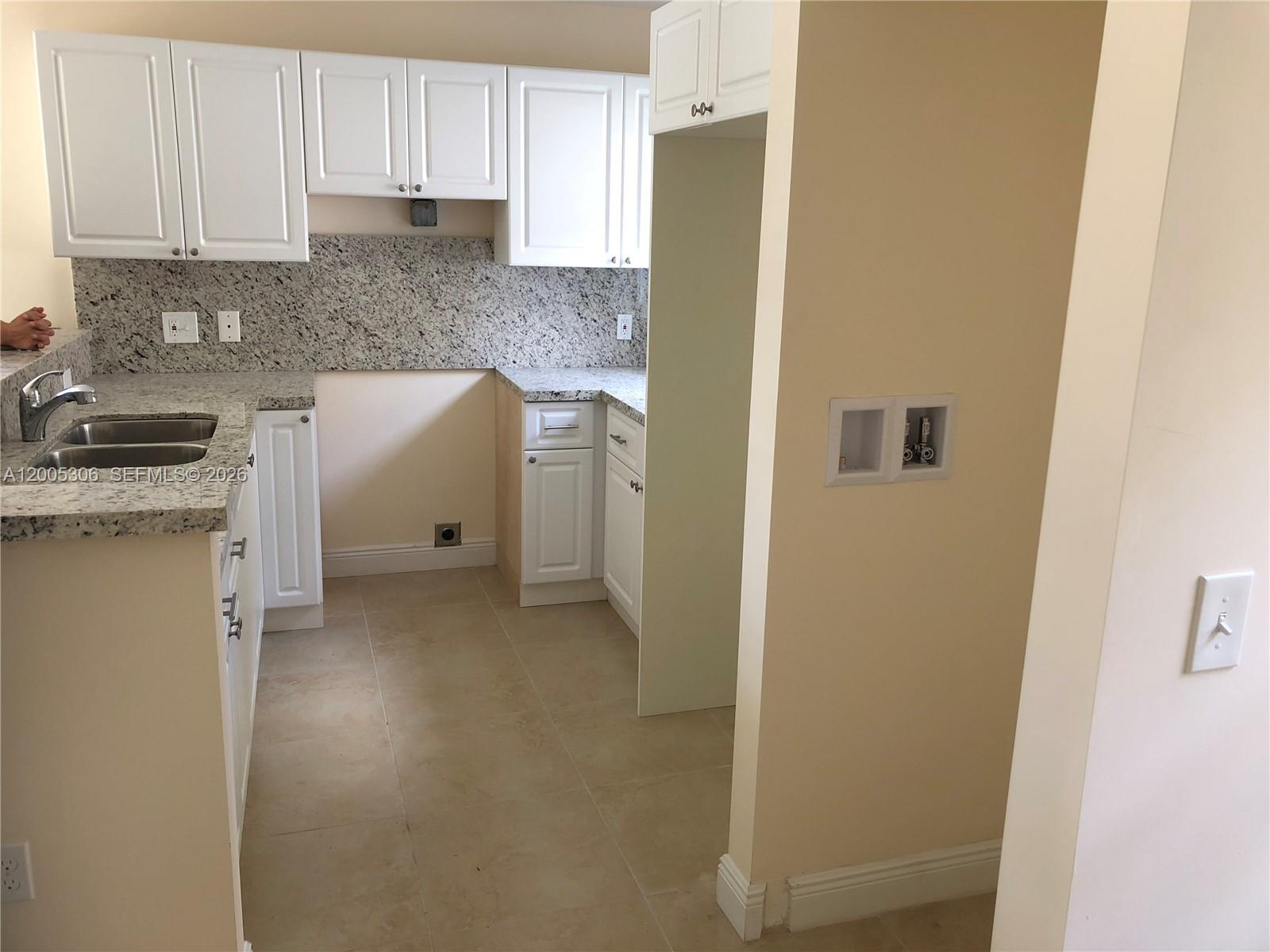 A kitchen with white cabinets and granite countertops opens into a tiled living area — 1565 NW 47th St # 1, Miami FL 33142, MIAMI, FL