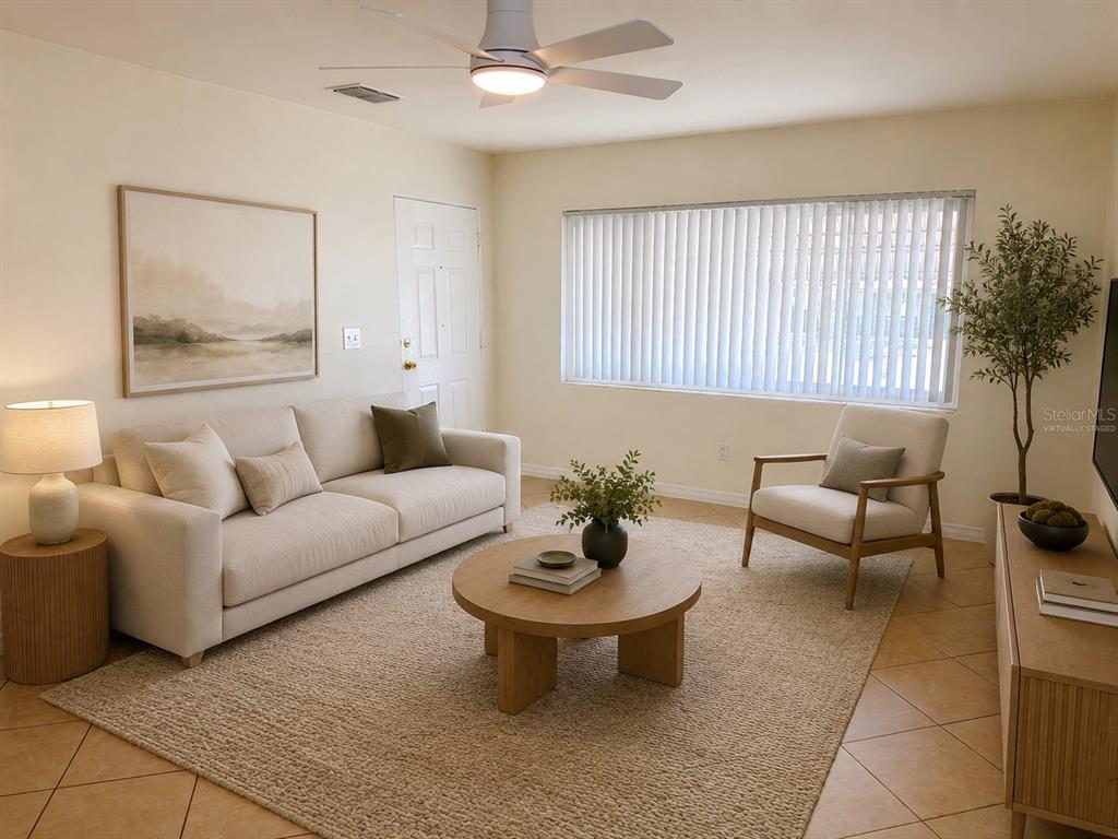 A living room features a beige sofa, a round wooden coffee table, and tile flooring — 1432 LOTUS PATH, CLEARWATER, FL