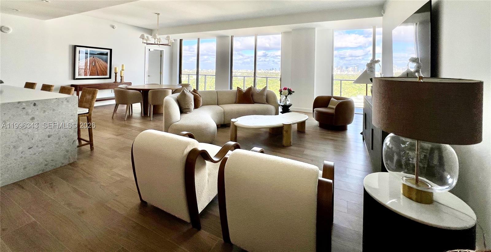A modern living room features a curved sofa, two armchairs, and floor-to-ceiling windows — 2678 Tigertail Ave # 2006, Coconut Grove FL 33133, COCONUT GROVE, FL