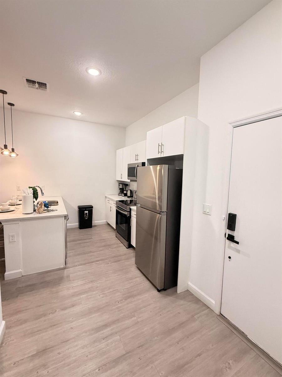 A kitchen features white cabinets, stainless steel appliances, and a breakfast bar with pendant lighting — 657 Trikomo Drive, Davenport FL 33896, DAVENPORT, FL