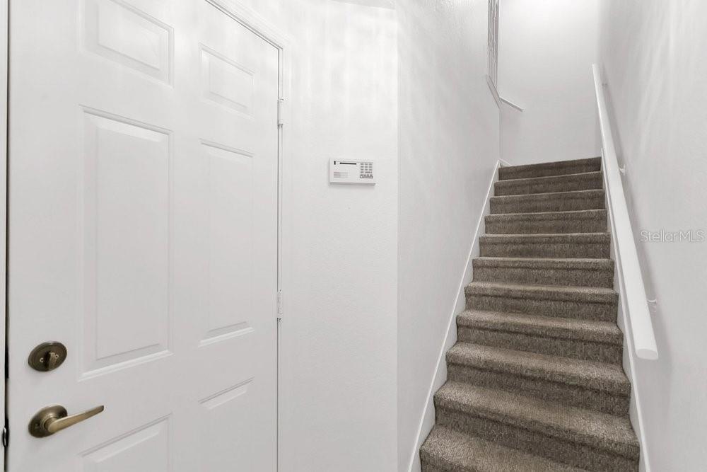 A white door stands next to a carpeted staircase with a white handrail — 1952 LEGACY COVE DRIVE UNIT 1952, MAITLAND, FL