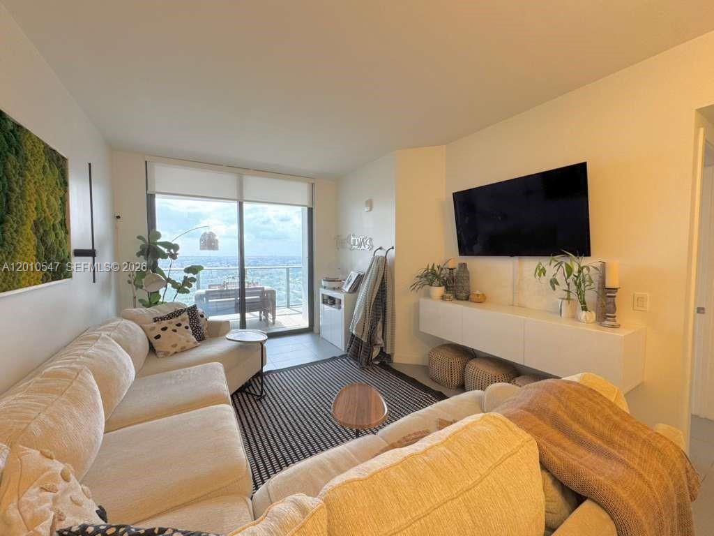 A living room features a sectional sofa, a wall-mounted television, and a balcony with views — 1600 NE 1st Ave # 3312, Miami FL 33132, MIAMI, FL