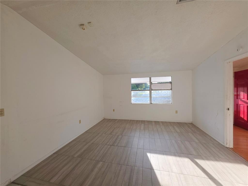 An empty room with white walls, light wood-look tile flooring, and a central window — 4037 LAS VEGAS DRIVE, NEW PORT RICHEY, FL