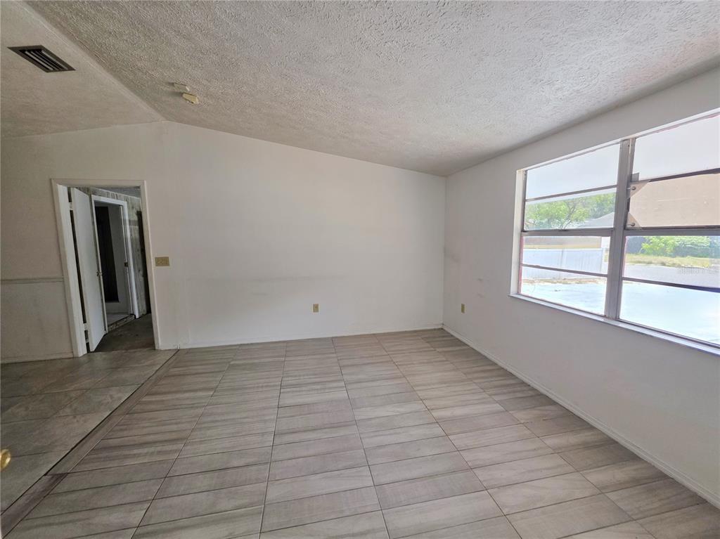 An empty room features white walls, light-colored tile flooring, and a large window — 4037 LAS VEGAS DRIVE, NEW PORT RICHEY, FL
