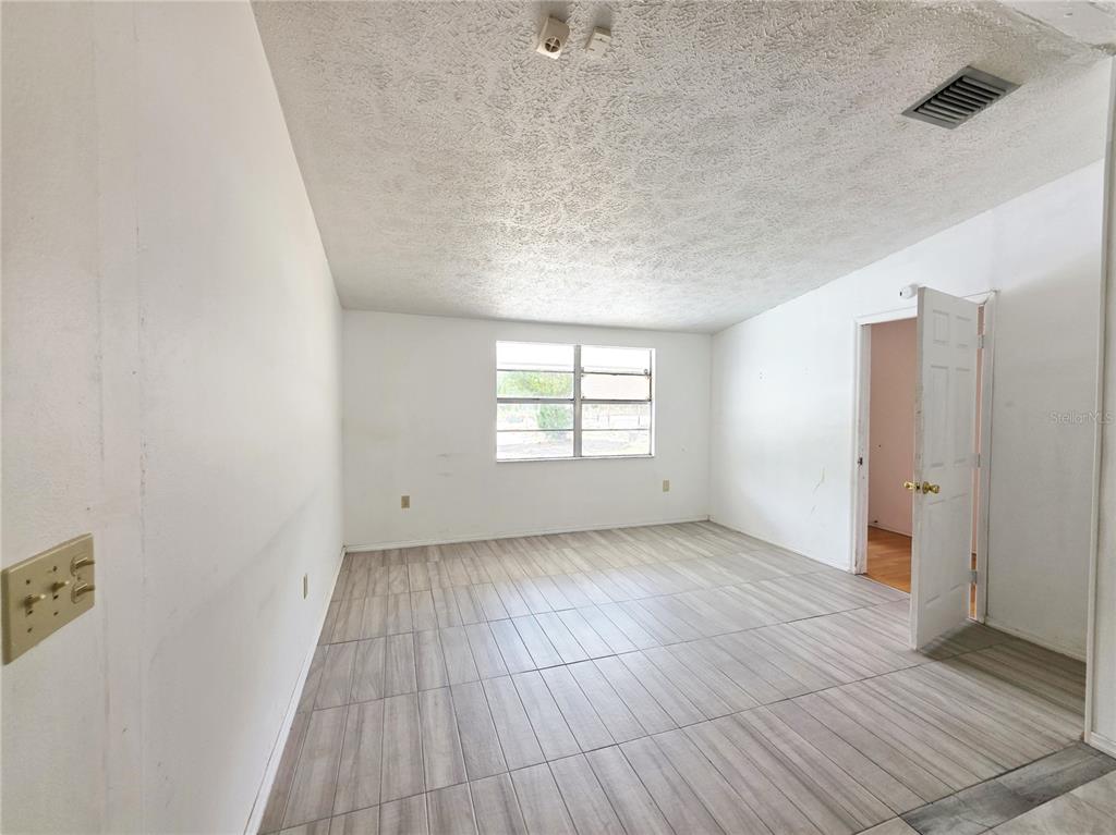 An empty room with light-colored tile flooring, white walls, and a single window — 4037 LAS VEGAS DRIVE, NEW PORT RICHEY, FL
