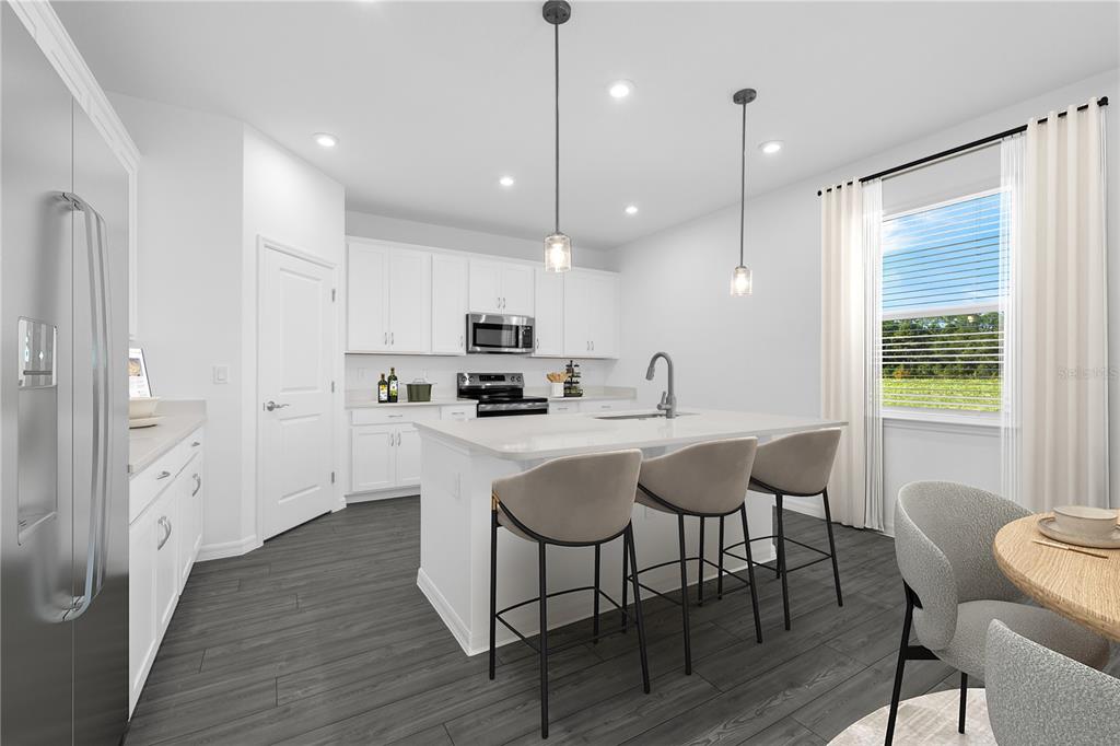 A modern kitchen features white cabinets, a central island with bar seating, and dark flooring — 1729 FLAG STREET, HAINES CITY, FL