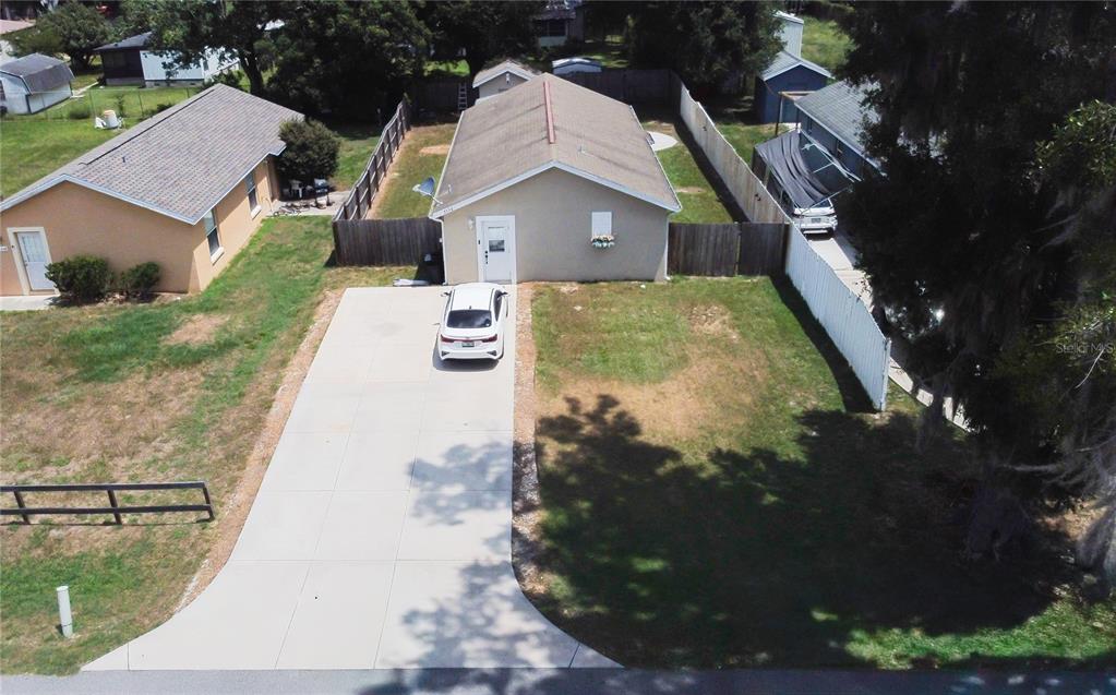 An aerial view shows a single-story house with a concrete driveway and a fenced yard — 3554 COUNTY ROAD 230C, WILDWOOD, FL