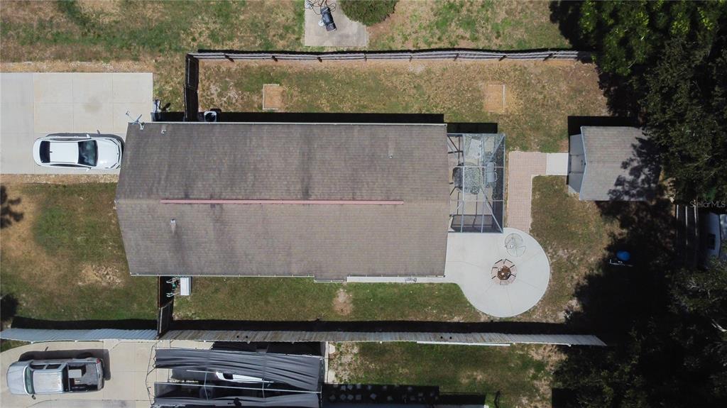 An aerial view shows a house with a screened porch, patio, and two parked cars — 3554 COUNTY ROAD 230C, WILDWOOD, FL