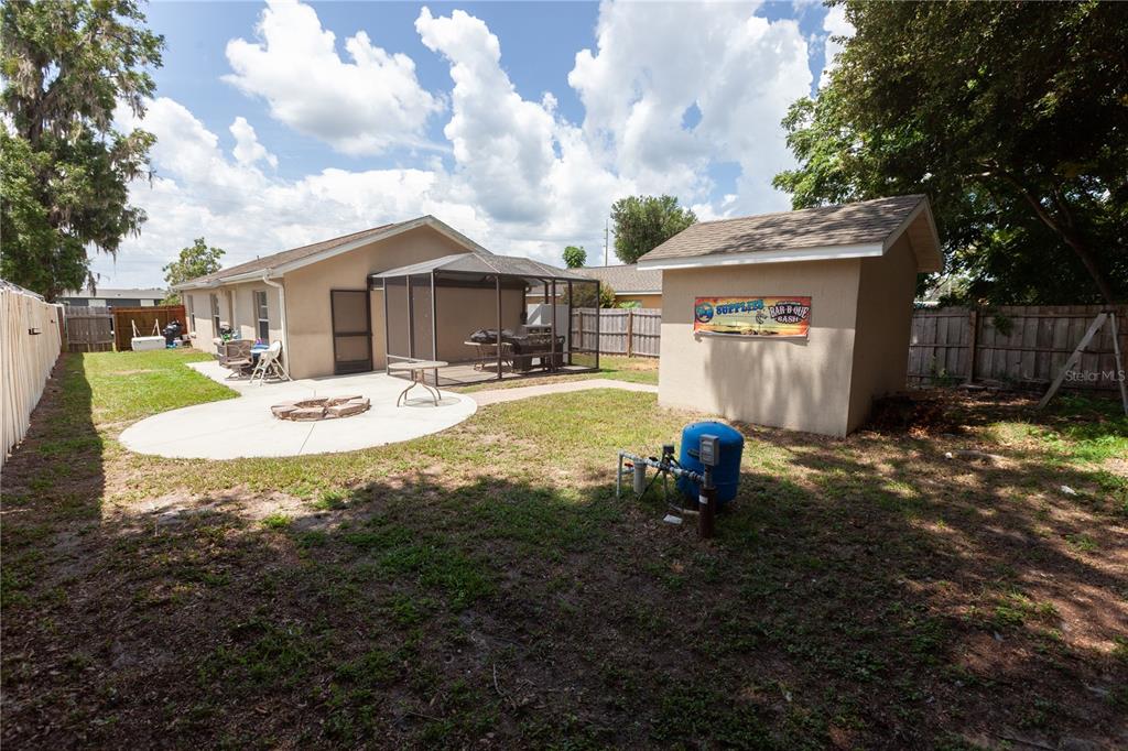 A backyard features a concrete patio with a fire pit, a screened enclosure, and a shed — 3554 COUNTY ROAD 230C, WILDWOOD, FL