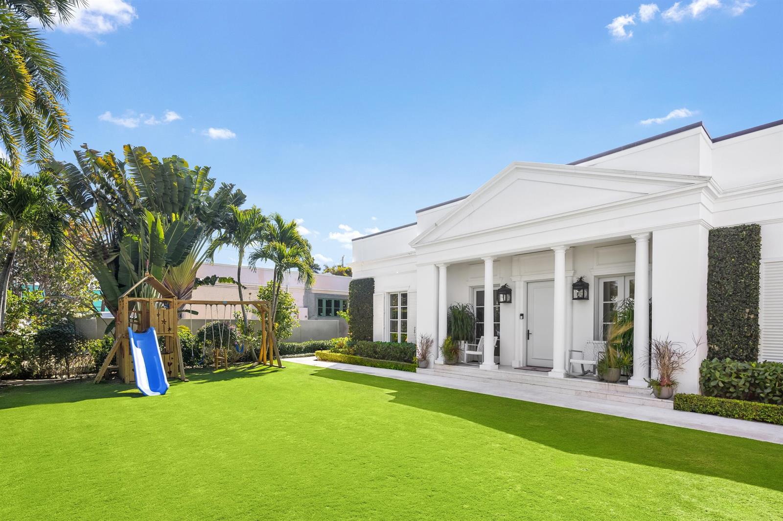 A white house with a columned porch overlooks a lawn featuring a wooden swing set — 208 Sandpiper Drive, Palm Beach FL 33480, PALM BEACH, FL