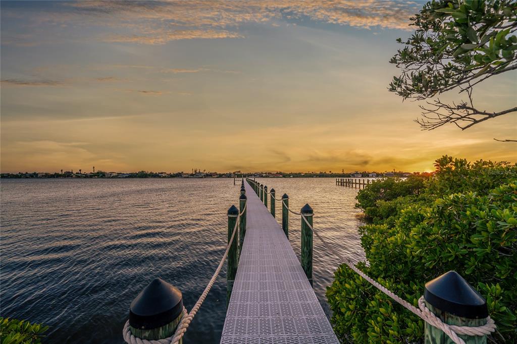 A long, narrow dock with rope railings extends over calm water toward a sunset horizon — BAYSHORE DRIVE, ENGLEWOOD, FL