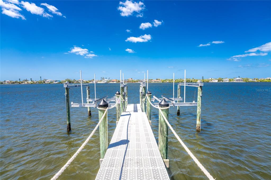 A metal boat dock extends into a calm body of water under a blue sky — BAYSHORE DRIVE, ENGLEWOOD, FL