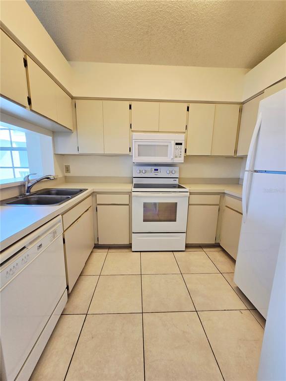 A living and dining area with vaulted ceilings, tile floors, and neutral furniture — 6802 STONES THROW CIRCLE N UNIT 14206, ST PETERSBURG, FL