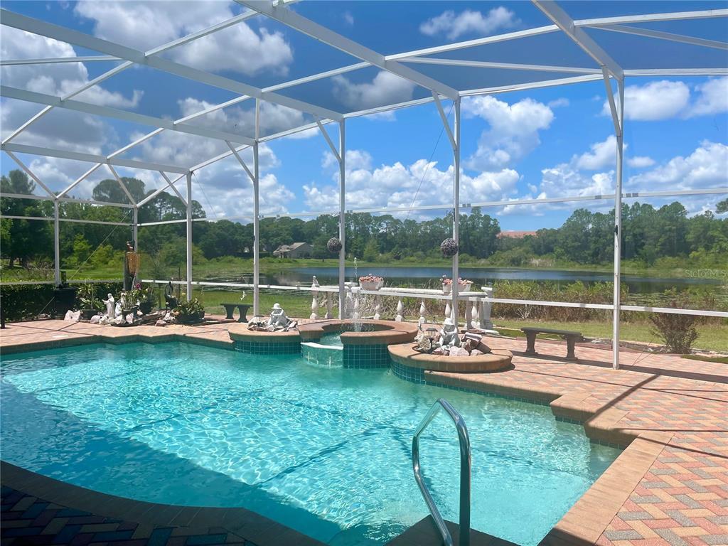 A swimming pool with a fountain and a screened-in patio overlooking a pond — 736 TIMACUAN BOULEVARD, LAKE MARY, FL
