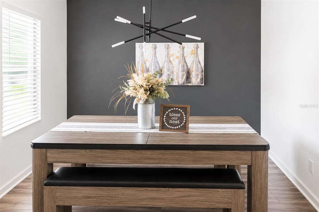 A dining room features a wood table, a bench, and a dark accent wall — 35584 EASTBROOK AVENUE, ZEPHYRHILLS, FL