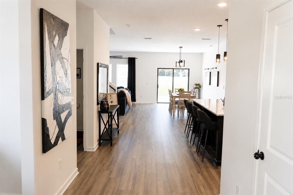 A view down a hallway into an open-concept kitchen and dining area with wood flooring — 35584 EASTBROOK AVENUE, ZEPHYRHILLS, FL