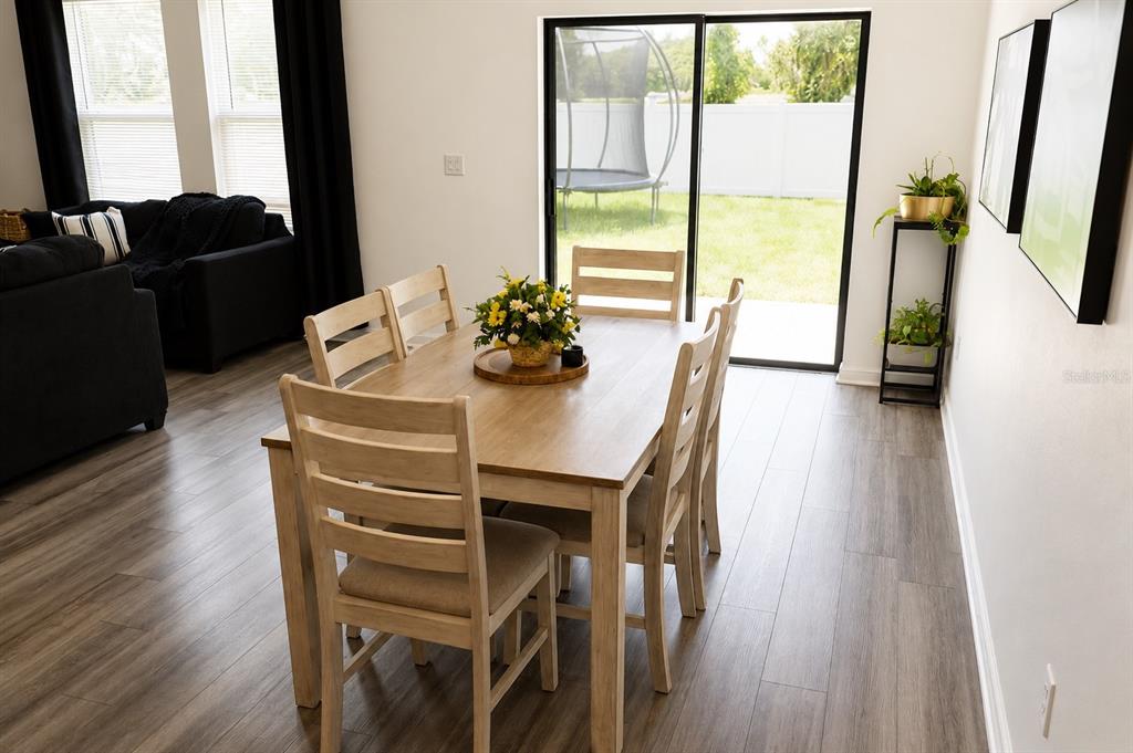 A dining room with a wooden table, six chairs, and a sliding glass door to a yard — 35584 EASTBROOK AVENUE, ZEPHYRHILLS, FL