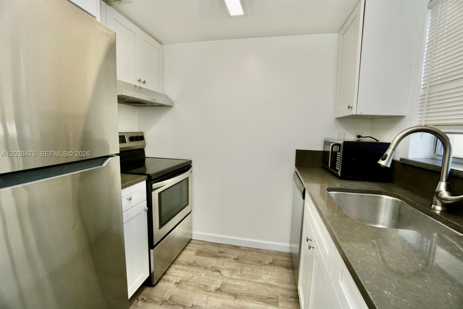 A galley kitchen features white cabinets, stainless steel appliances, and dark gray countertops — 8500 SW 109th Ave # 225, Miami FL 33173, MIAMI, FL