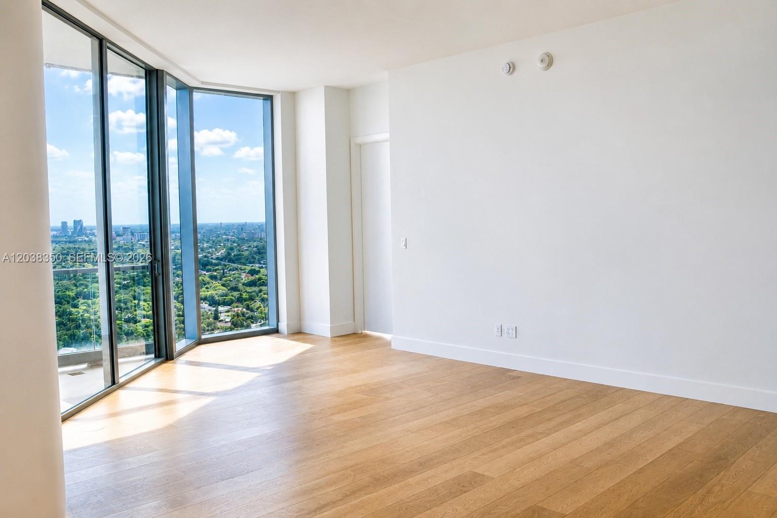 An empty room with light wood floors, white walls, and floor-to-ceiling windows overlooking a city — 175 SE 25th Rd # 3103, Miami FL 33129, MIAMI, FL