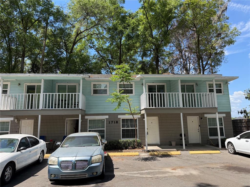 A two-story apartment building with light blue siding, white railings, and a parking lot — 1718 SW 69 TERRACE, GAINESVILLE, FL