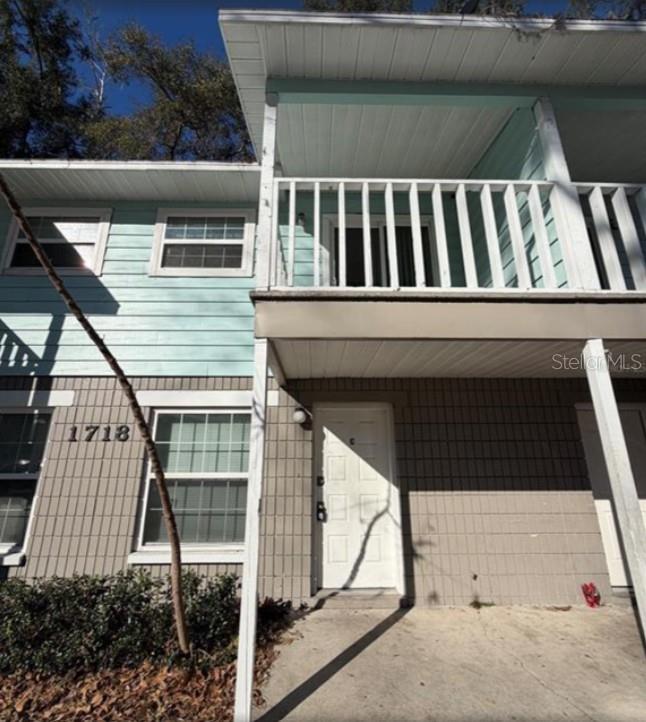 A two-story building exterior features light blue siding, gray brick, and a covered balcony — 1718 SW 69 TERRACE, GAINESVILLE, FL