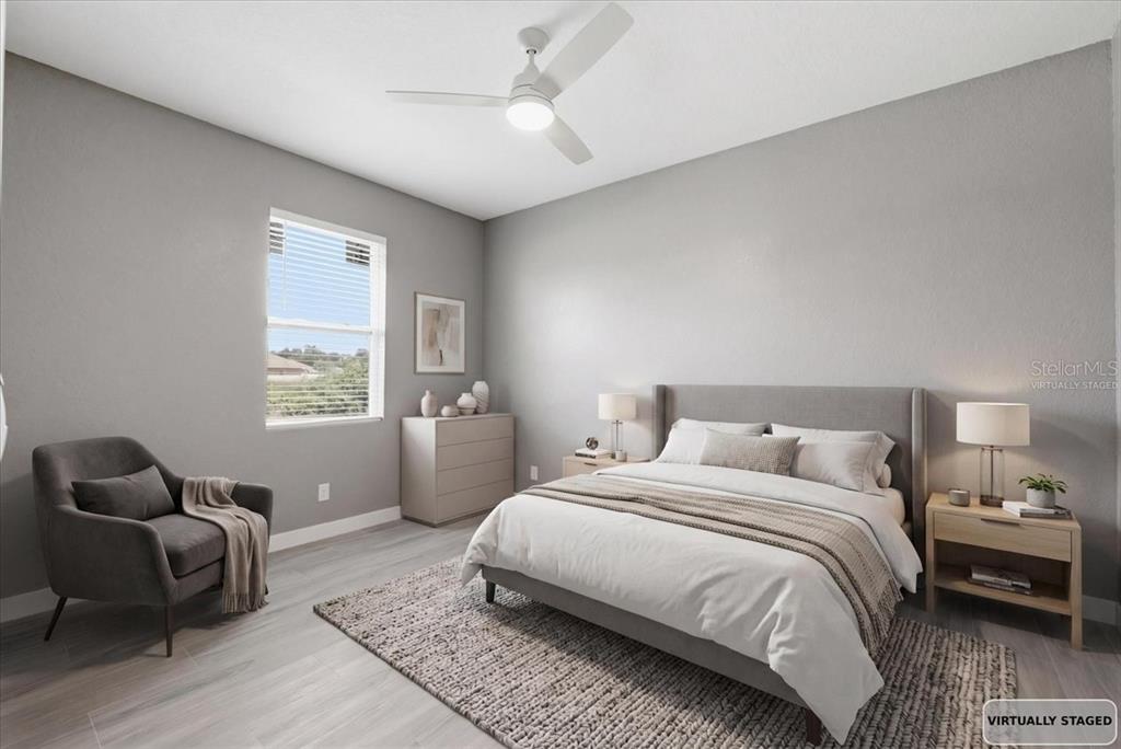A bedroom with light gray walls, wood-look flooring, a bed, a chair, and a dresser — 2683 HOPWOOD ROAD, NORTH PORT, FL