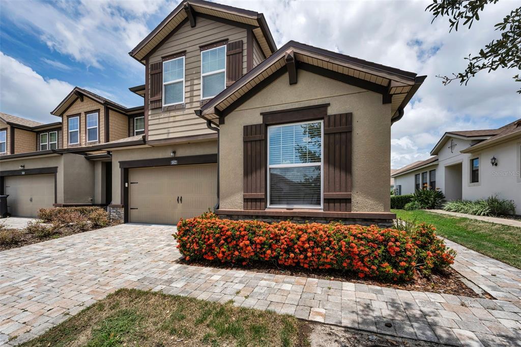 A two-story suburban house with a tan stucco facade, brown shutters, and a paved driveway — 11823 BROOKSIDE DRIVE, BRADENTON, FL