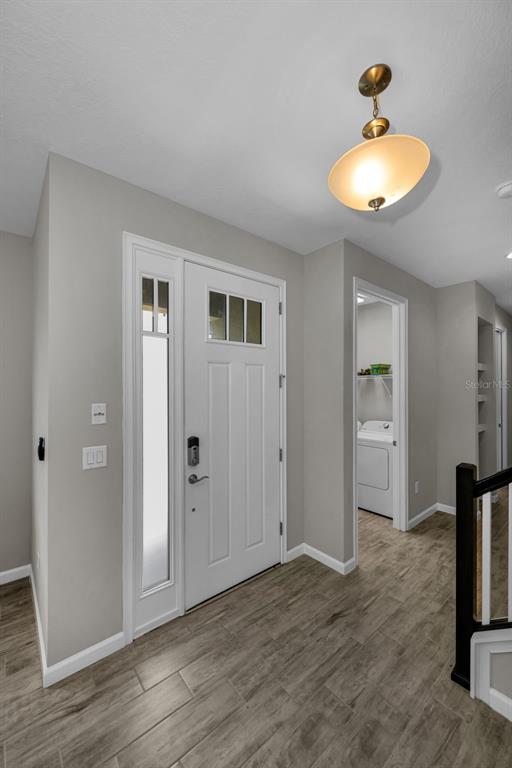 An entryway with a white front door, wood-look tile flooring, and a pendant light fixture — 11823 BROOKSIDE DRIVE, BRADENTON, FL