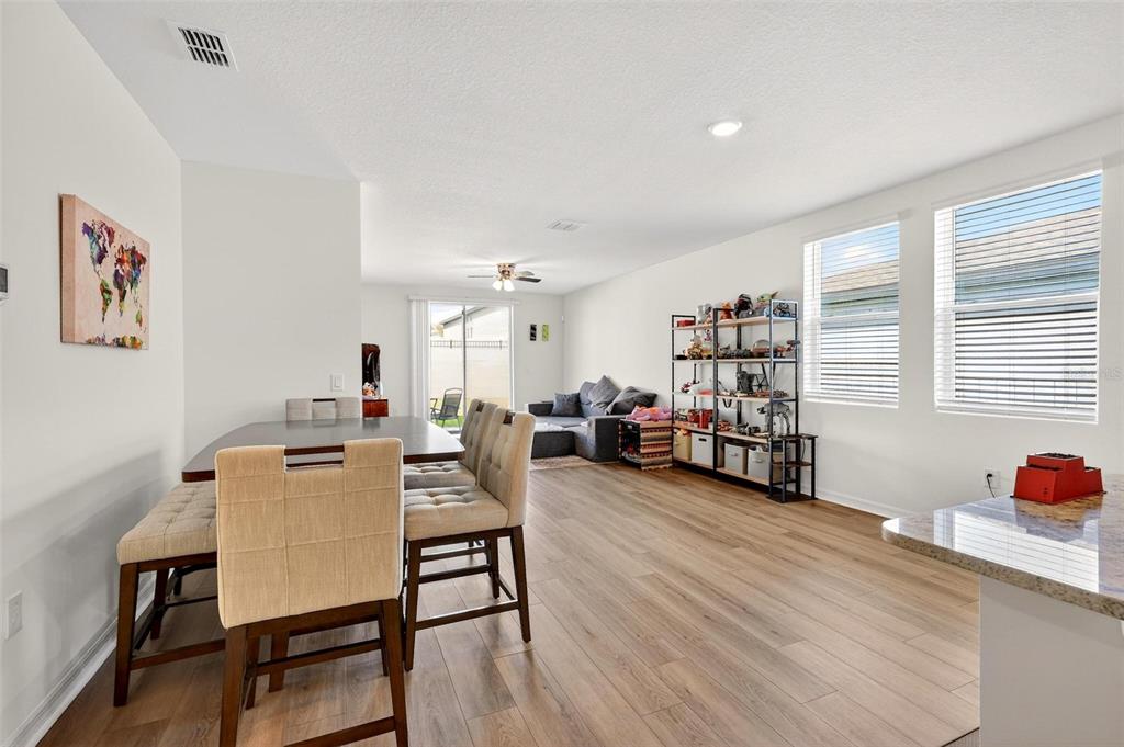 An open-concept dining and living area features light wood-look flooring and large windows — 2514 MOOSE TRAIL PLACE, DAVENPORT, FL